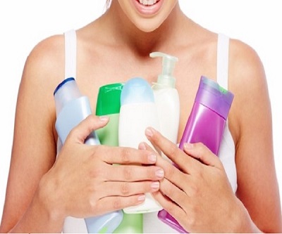 A woman holding various beauty and wellness products like shampoo, conditioner, body lotion, etc.