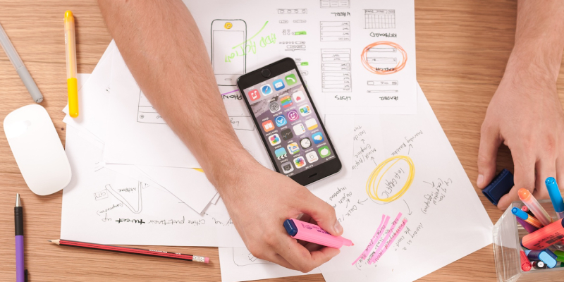 A man planning for an event venue with his paper drawings and mobile