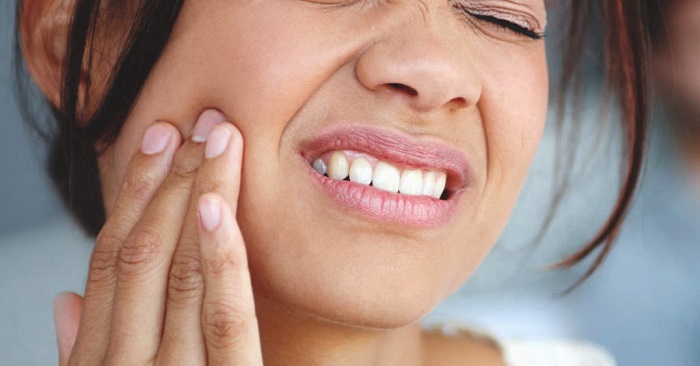 A woman (face partially seen) in pain because of tooth ache.